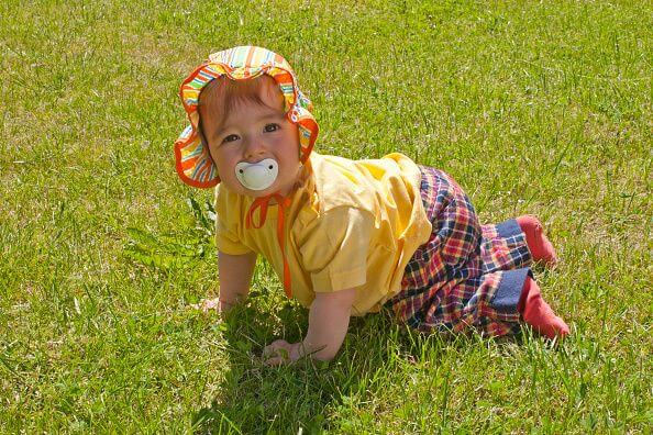Baby girl crawling along lawn
