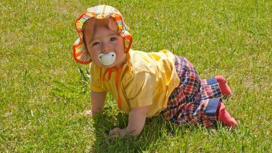 Baby girl crawling along lawn