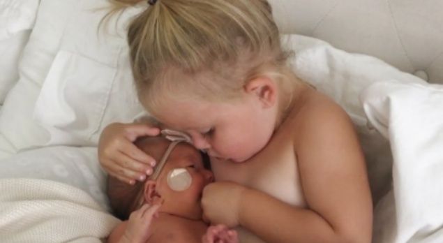 Una pequeña intenta amamantar a su hermanita para tranquilizarla
