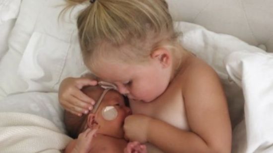 Una pequeña intenta amamantar a su hermanita para tranquilizarla
